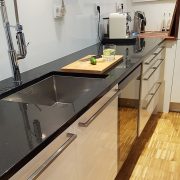 Küchenblock mit schwarzer Natursteinarbeitsplatte und Edelstahlunterspüle